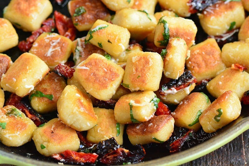 crispy cauliflower gnocchi in a pan with sundried tomatoes, basil and Parmesan