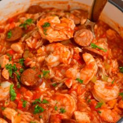 scooping a ladle-full of jambalaya out of the pot using a ladle with a wooden spoon