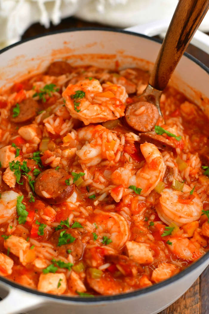 scooping a ladle-full of jambalaya out of the pot using a ladle with a wooden spoon