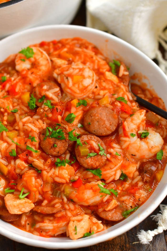 closer view of jambalaya sprinkled with a little parsley in a a white bowl with a spoon in the bowl