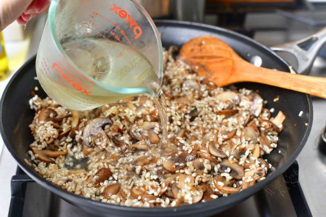 pour white wine into a skillet of mushroom risotto