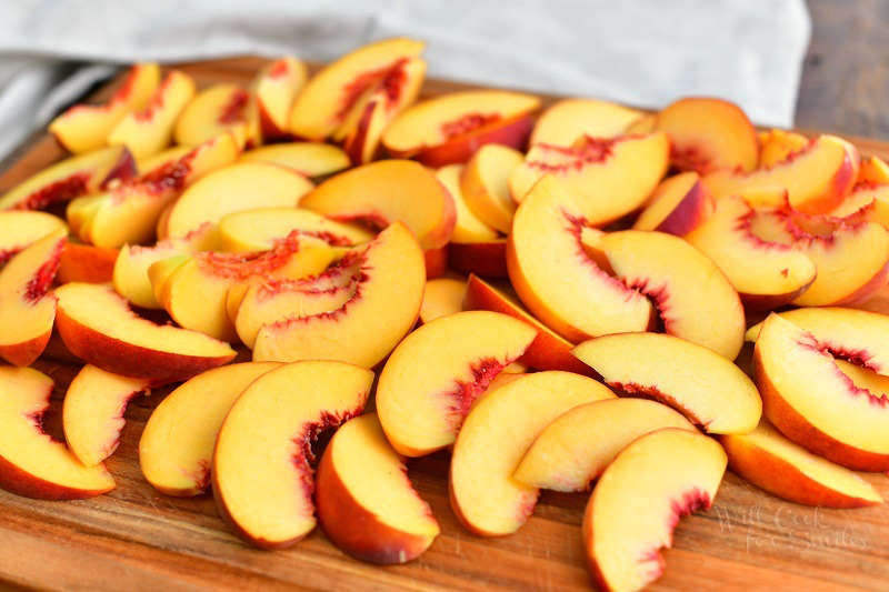 many slices of peaches spread out on the wooden cutting board