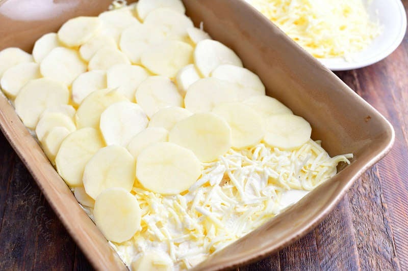 slices of white potato layered over shredded cheese in baking dish