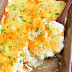 overhead photo: wooden spoon holds a serving of potato casserole in the casserole dish