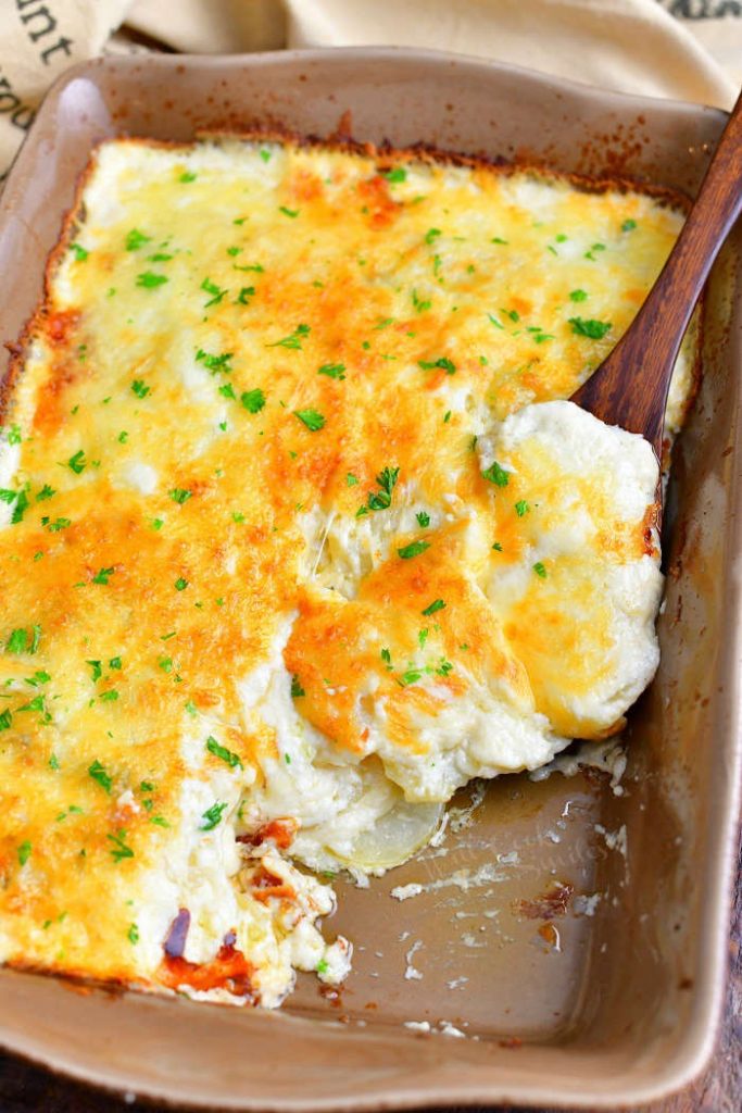 overhead photo: wooden spoon holds a serving of potato casserole in the casserole dish