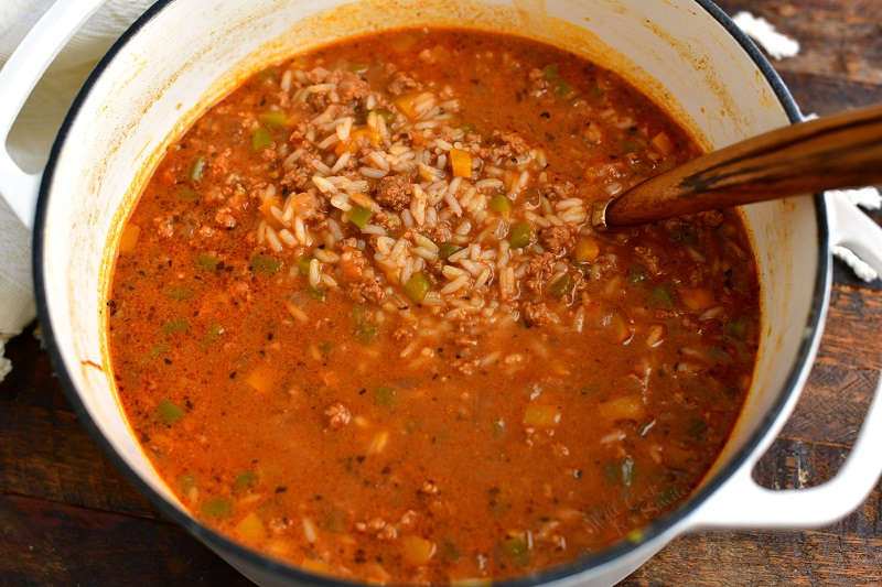 overhead: large pot of tomato-based soup with ground beef, rice, and bell peppers
