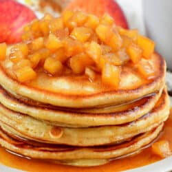 squared off image of closeup stack of pancakes and apple topping