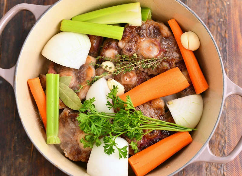 beef bones, chopped vegetables, and fresh herbs in large pot for stock