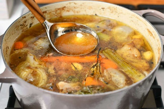 simmering water, beef bones, carrots, onion, celery and rosemary in large white pot