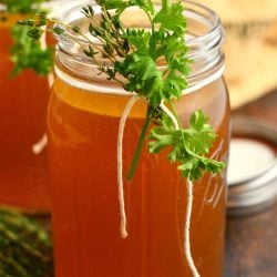 homemade stock in glass canning jar garnished with fresh herbs