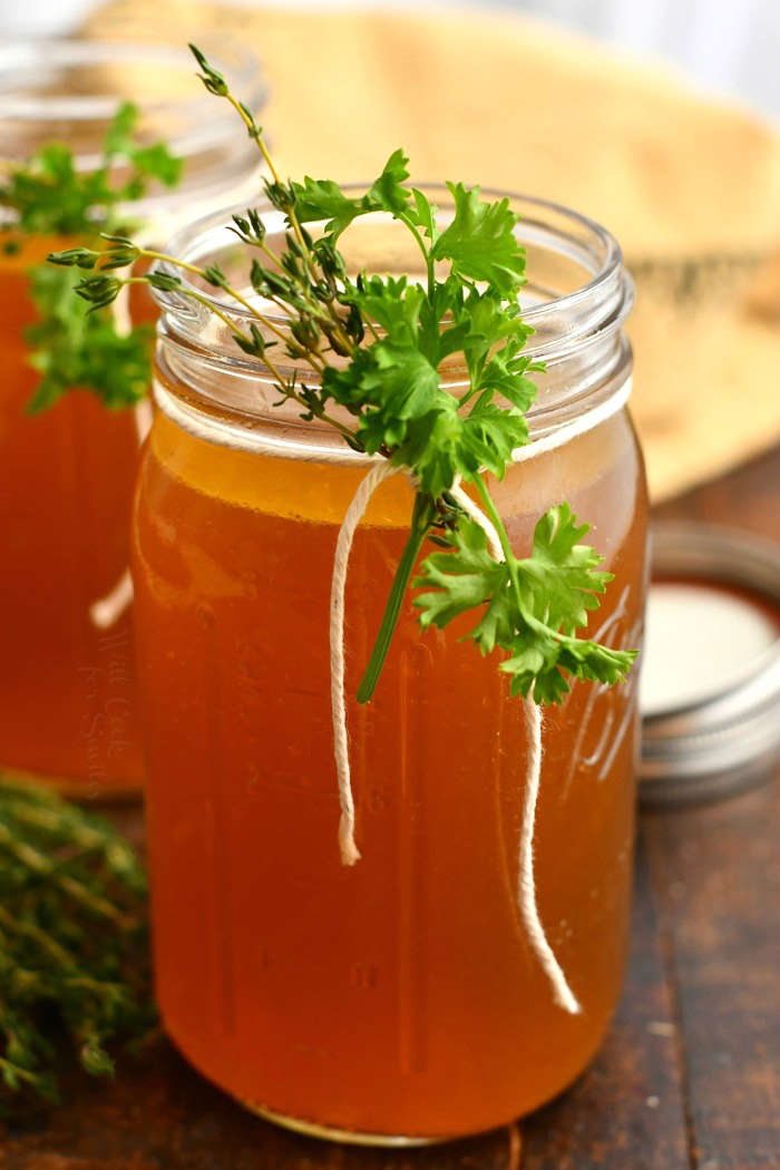 homemade stock in glass canning jar garnished with fresh herbs