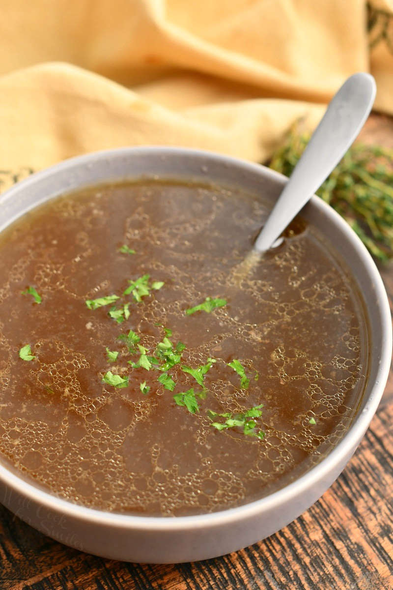 looking down at spoon in white soup bowl with homemade beef stock