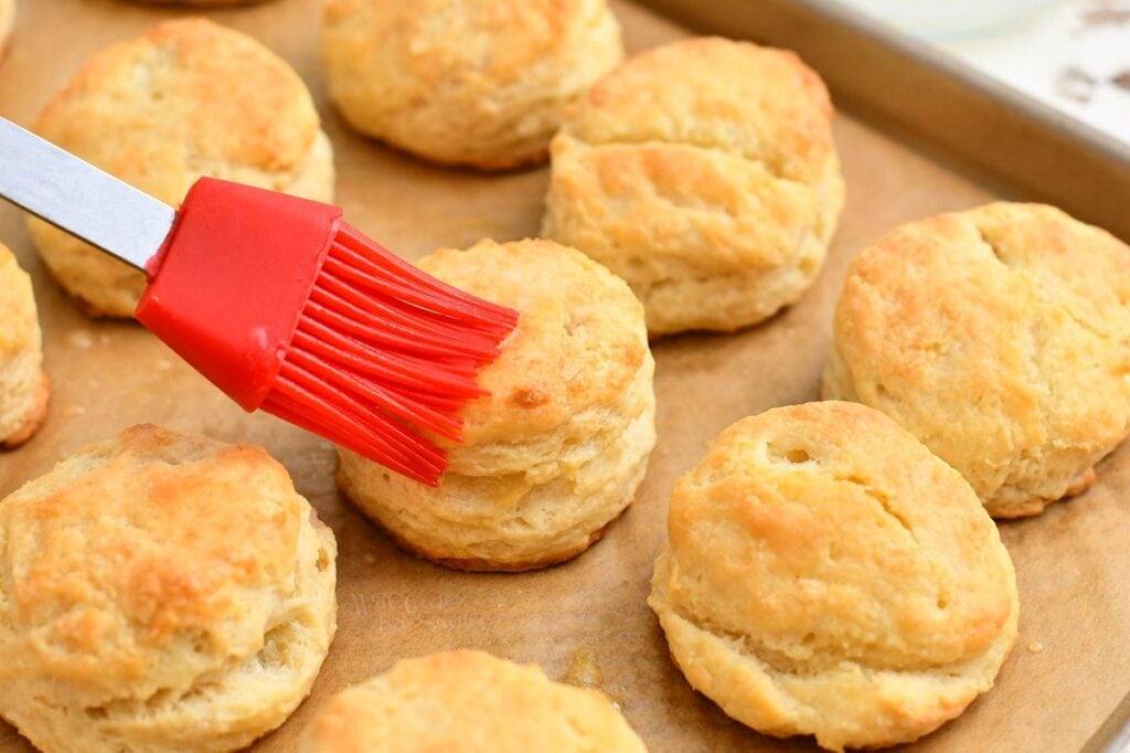 brushing tops of homemade biscuits with melted butter