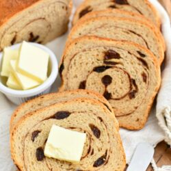 slices of freshly baked cinnamon swirl bread next to tabs of butter in white dish