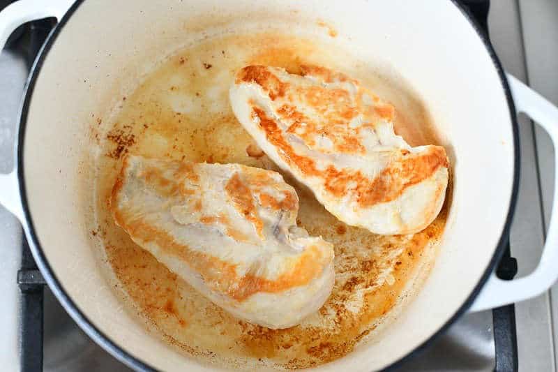 overhead: seared chicken breasts in large white pot