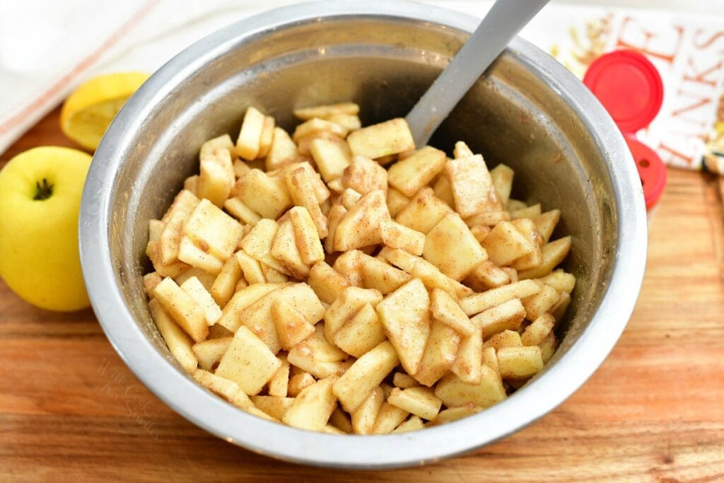 stirring fresh apple slices in a bowl with cinnamon sugar mixture