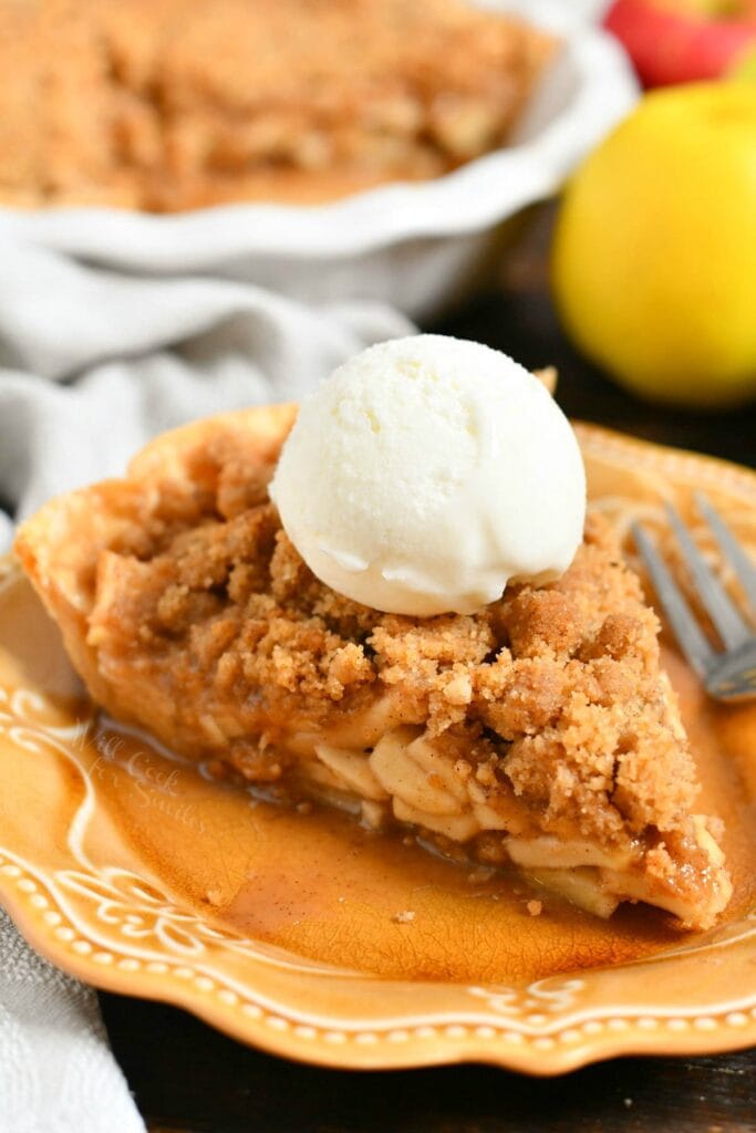 plated slice of homemade apple dessert with crumble topping and vanilla ice cream on top