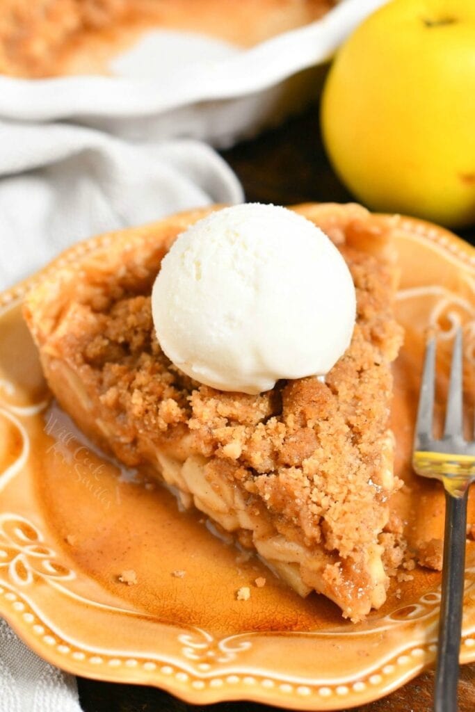 slice of Dutch apple pie with scoop of vanilla ice cream on brown plate