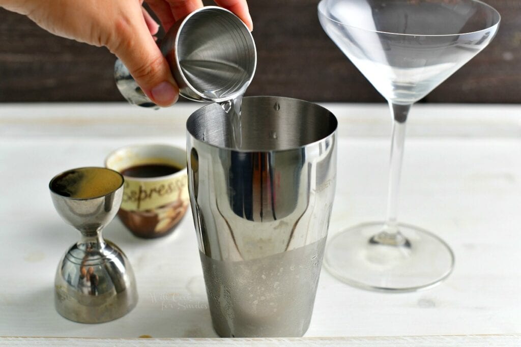 pouring clear liquor into the cocktail shaker