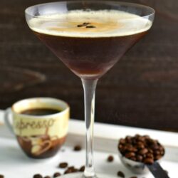 side view of tall martini glass with the cocktail and coffee beans and espresso shot next to it