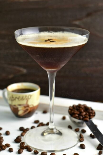 side view of tall martini glass with the cocktail and coffee beans and espresso shot next to it