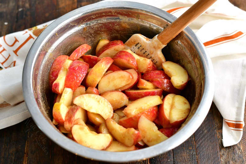 mixing spatula stirring red apple slices with cinnamon spice mixture