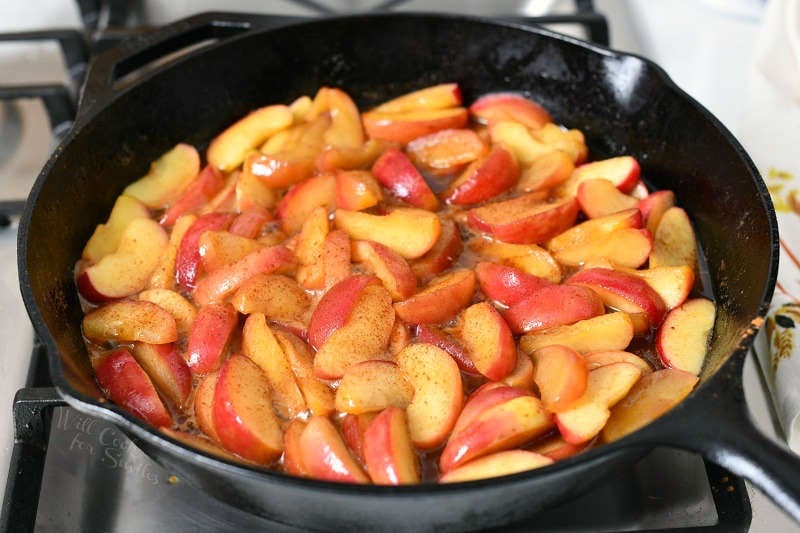 side view: frying sliced red apples in cast iron pan