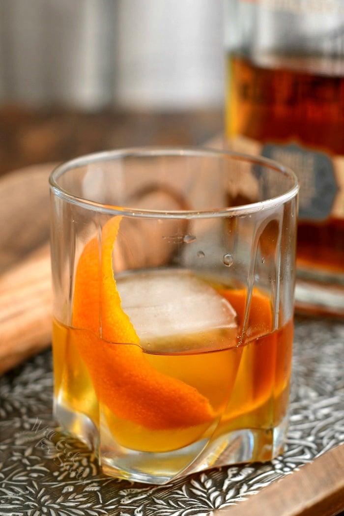 side view: whiskey old fashioned in low ball cocktail glass with orange peel