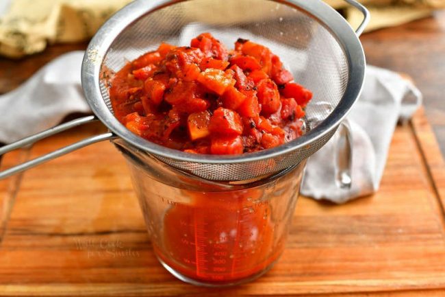 straining diced tomatoes through fine mesh strainer into measuring cup