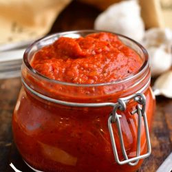 homemade pizza sauce with tomato paste in small glass jar on wooden counter top