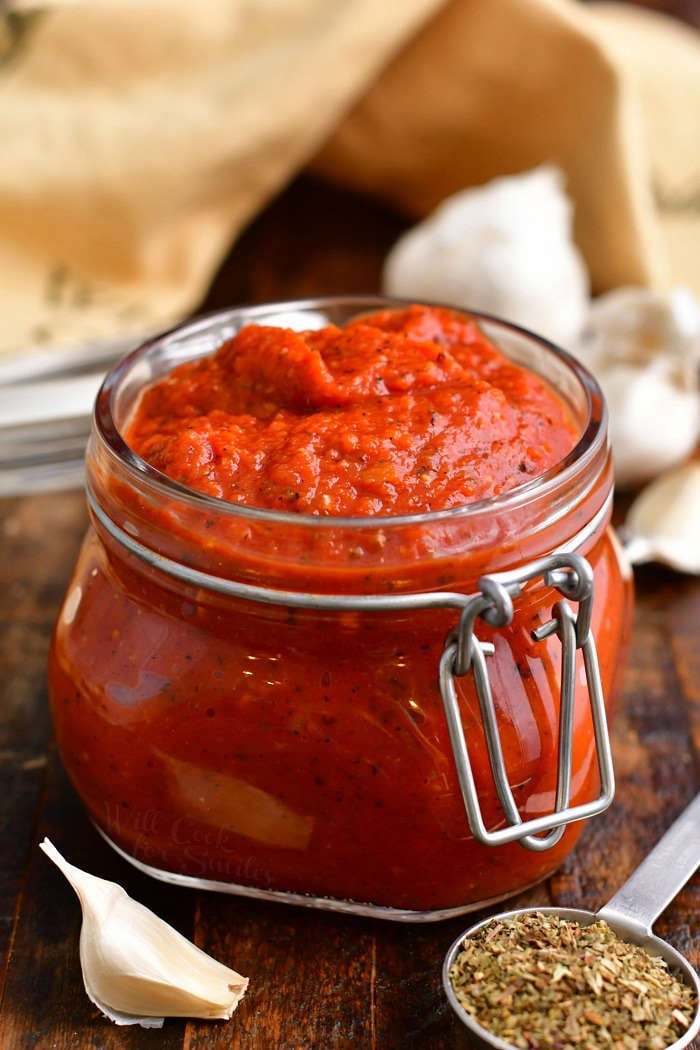 homemade pizza sauce with tomato paste in small glass jar on wooden counter top