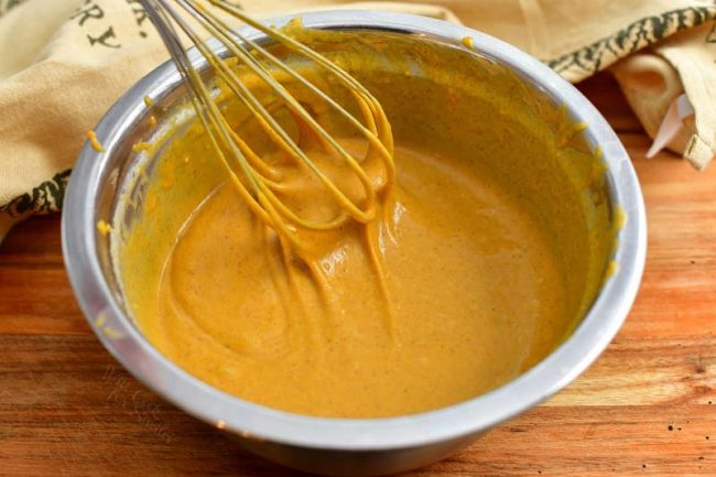 whisking batter in large metal mixing bowl for an easy pumpkin bread recipe