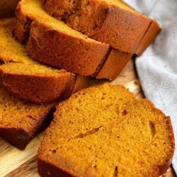 thick slices of moist pumpkin bread on wooden serving board with white linen napkin