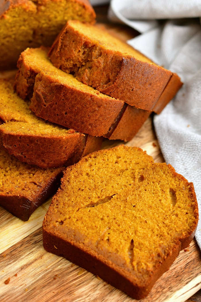 thick slices of moist pumpkin bread on wooden serving board with white linen napkin
