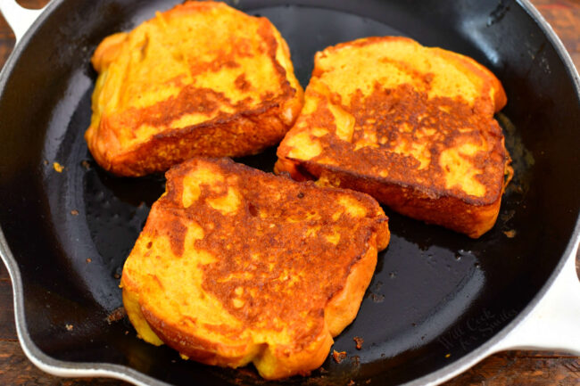 three slices of pumpkin French toast cooking in a skillet