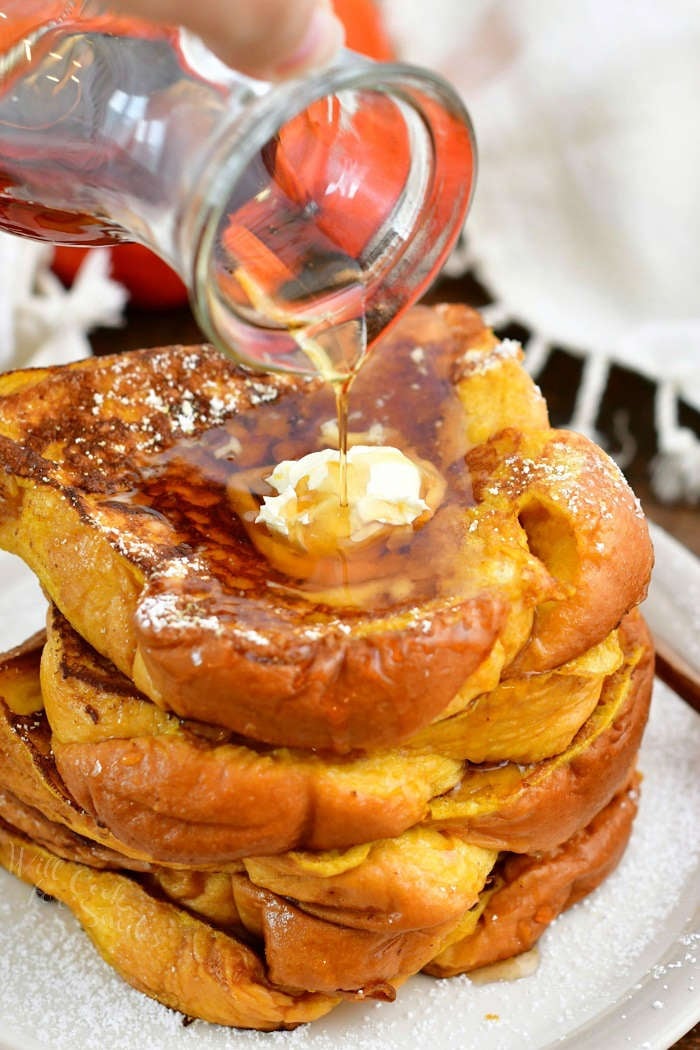 pouring syrup onto the stack of French Toast out of a glass jar