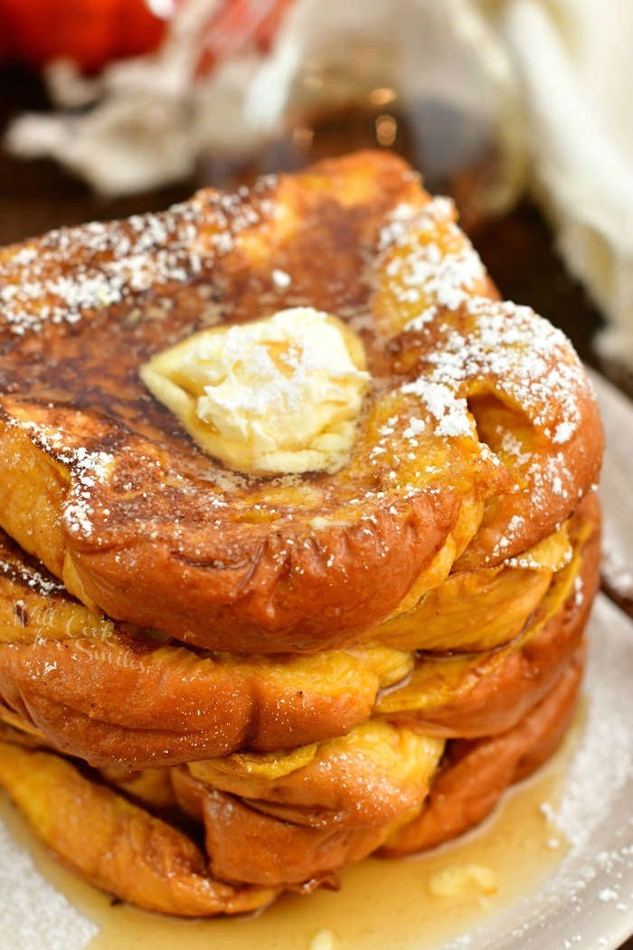 closeup top view of stack of French Toast topped with butter, syrup, and powdered sugar