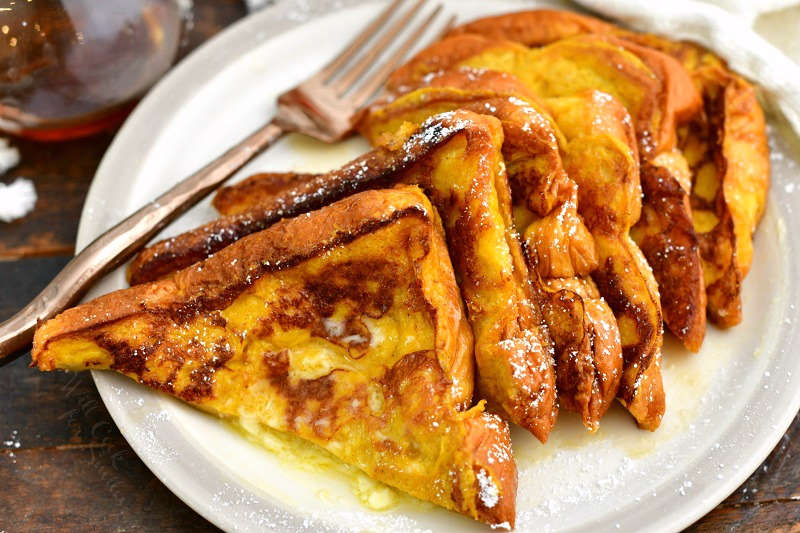 sliced French Toast into triangles stacked side by side on a white plate