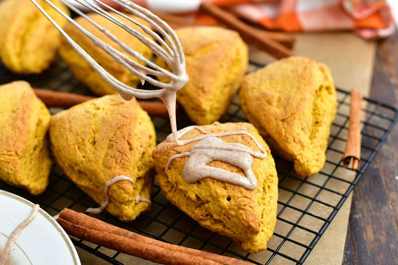 cinnamon glaze dripping from whisk onto a scone