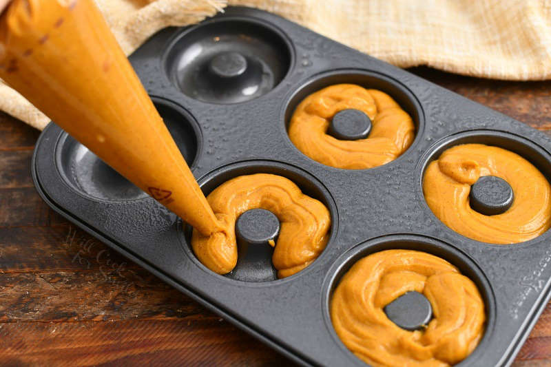 using pastry bag to fill the wells of doughnut pan for pumpkin spice latte