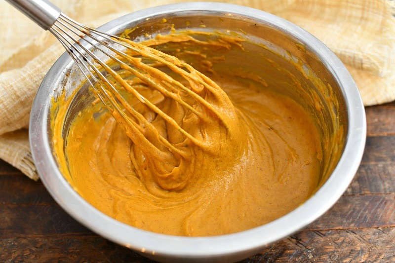 whisking pumpkin batter in a bowl to make a baked donuts recipe