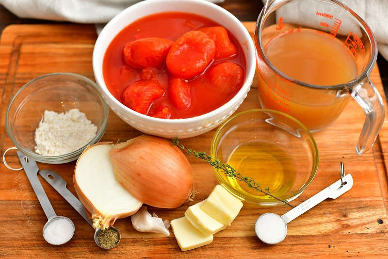 ingredients in measuring cups, spoons, and bowls to make homemade tomato soup