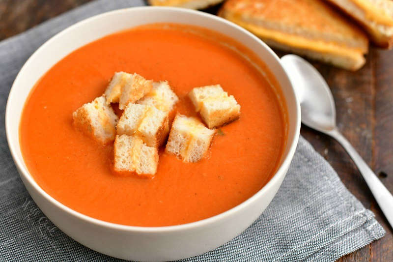 white bowl of soup made with canned tomatoes - spoon next to bowl