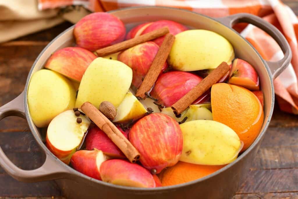 large pot of yellow and red apples, cut into quarters with cinnamon sticks and oranges