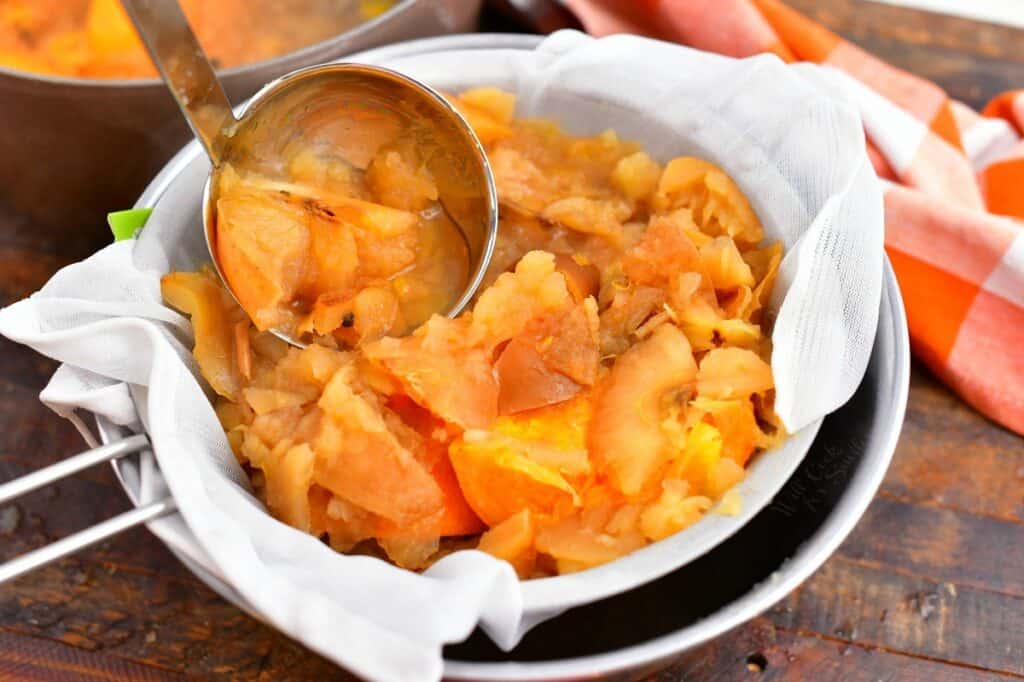 ladling cooked apples to cheesecloth lined strainer