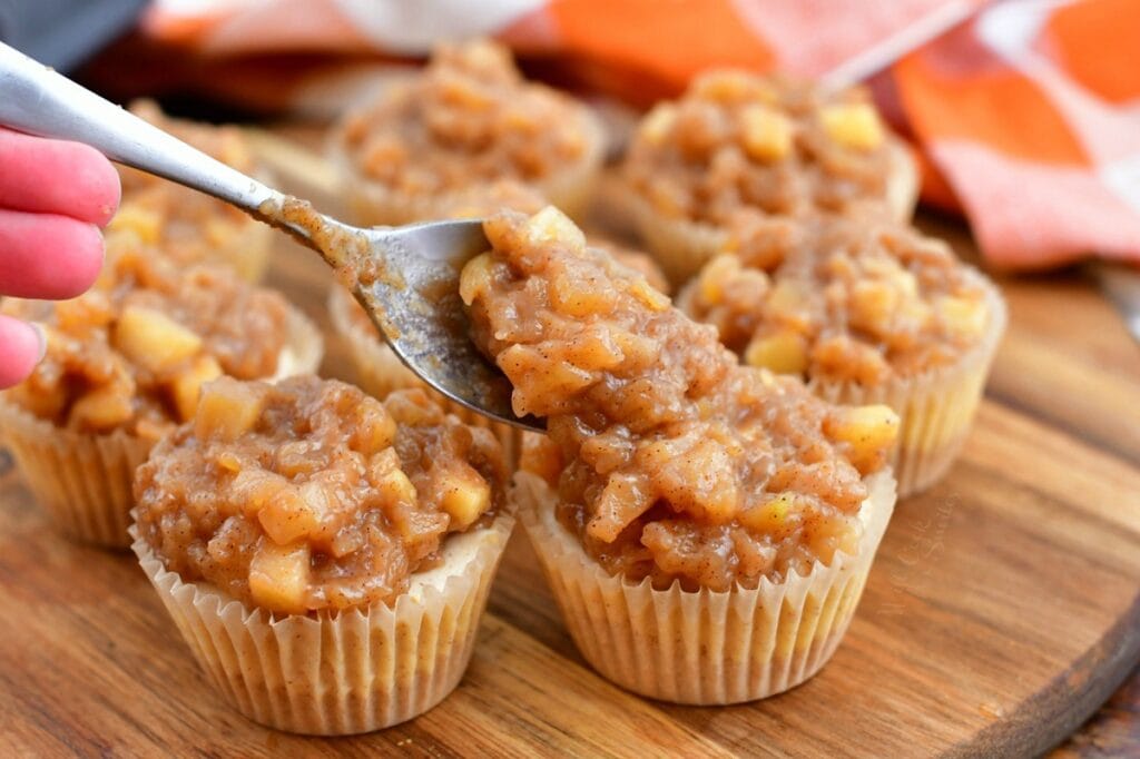 making mini cheesecake recipe by spooning apple pie filling onto the individual desserts