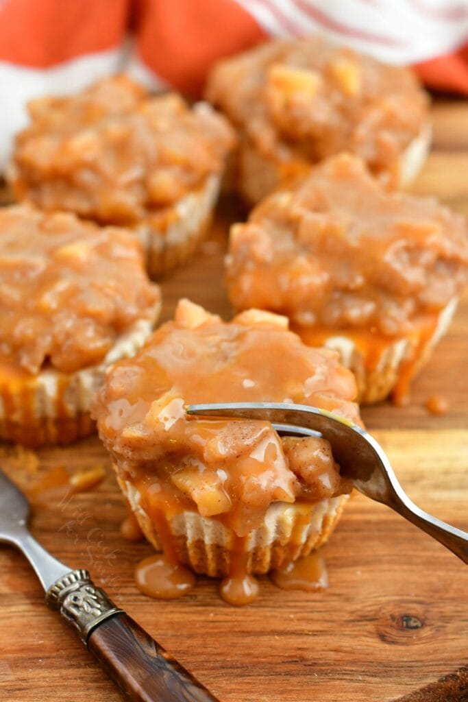 fork cutting into mini cheesecake topped with apple pie filling