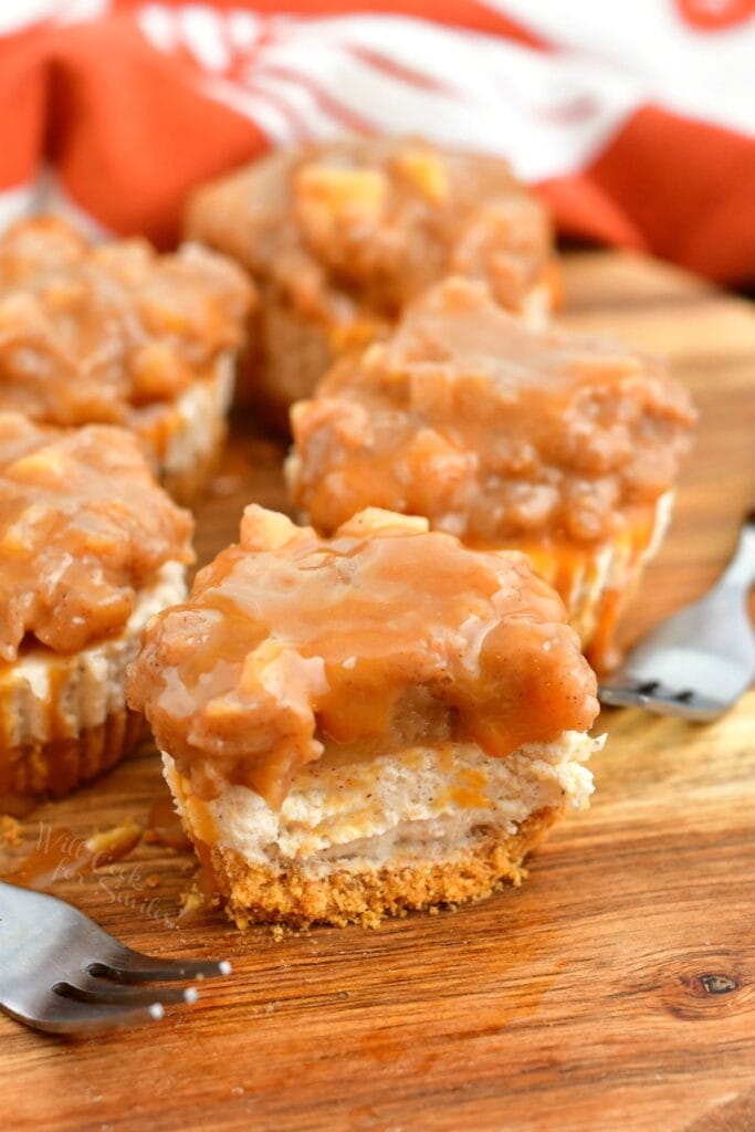 individual cheesecakes topped with caramel, one with a bite taken from it