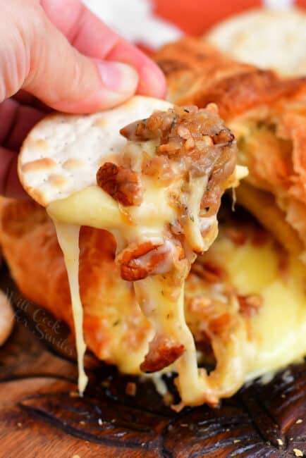 warm brie on cracker with nuts and caramelized onions