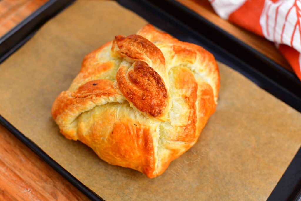 golden brown baked brie puff pastry appetizer on baking sheet